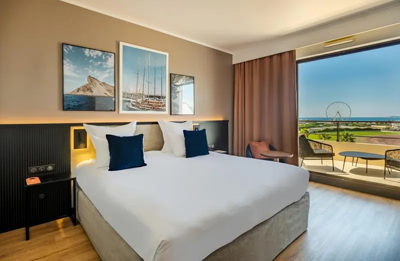 Chambre lumineuse avec un grand lit et une vue sur la mer.