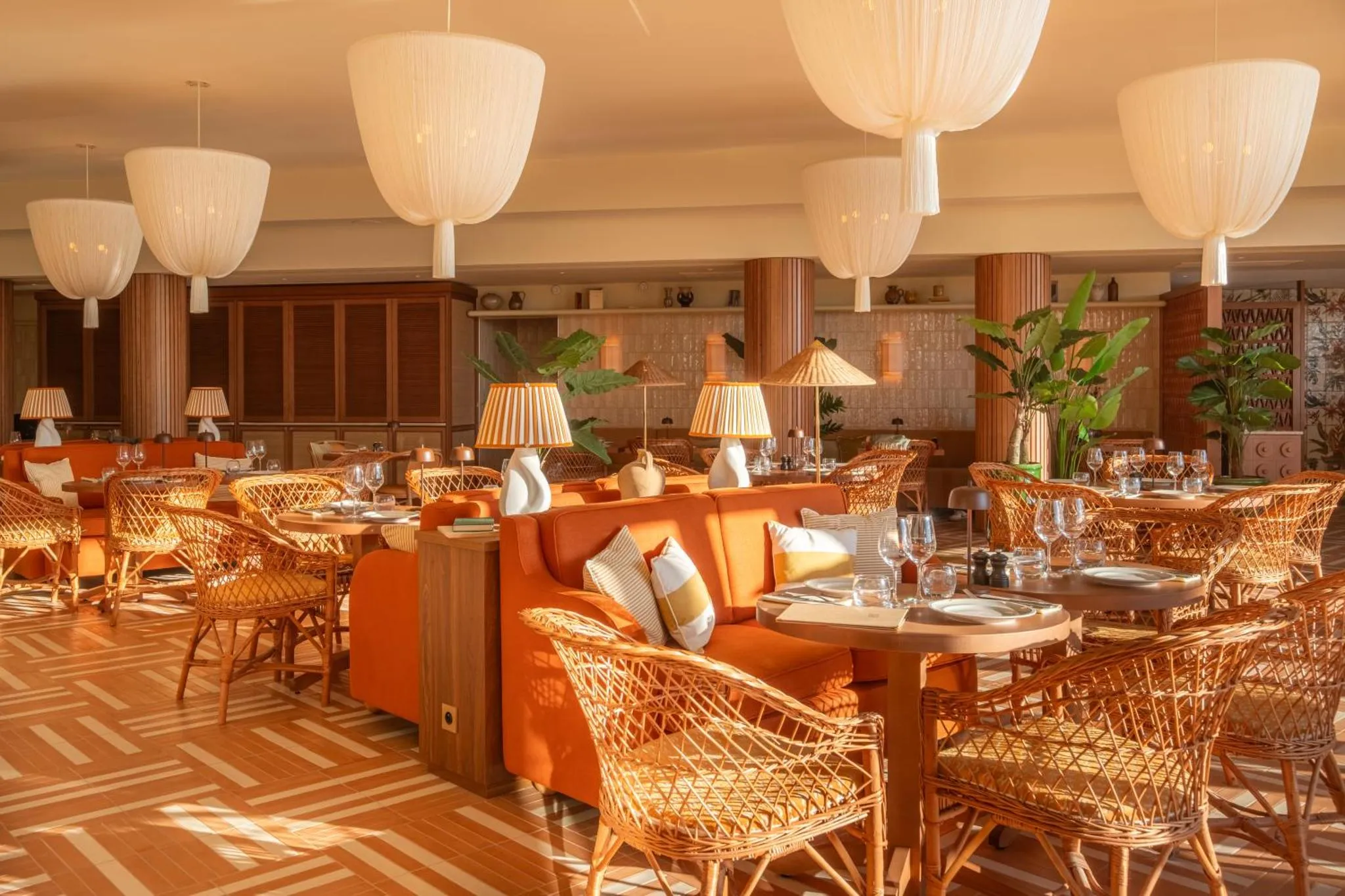 Une salle à manger lumineuse avec des tables dressées et des canapés confortables.