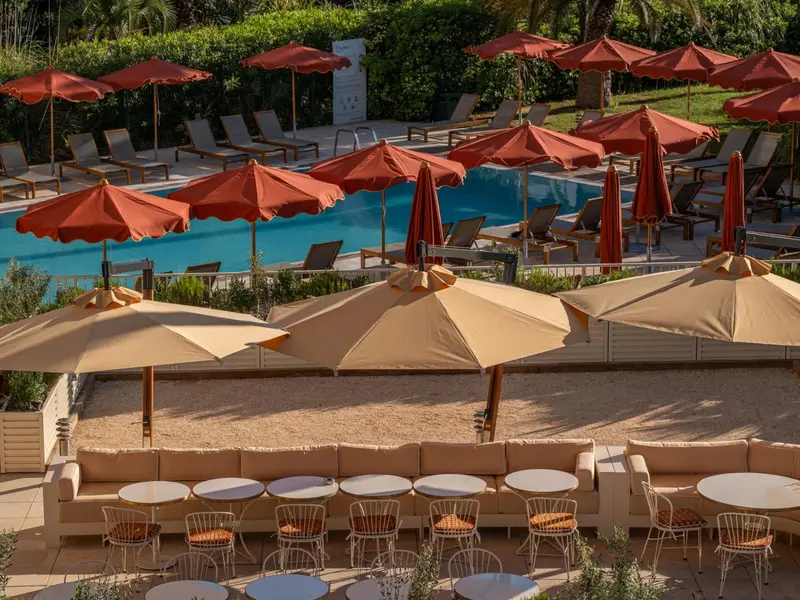 Terrasse aménagée avec parasols et mobilier de détente près d'une piscine.