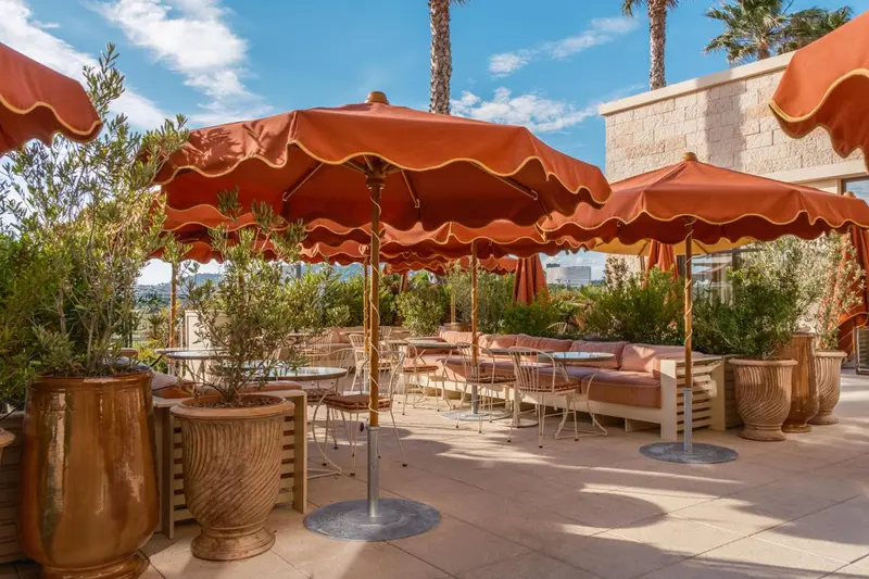 Terrasse ombragée avec tables et canapés en extérieur.