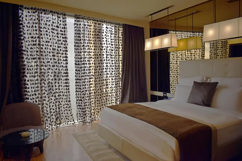 Une chambre moderne avec un grand lit et de larges rideaux.