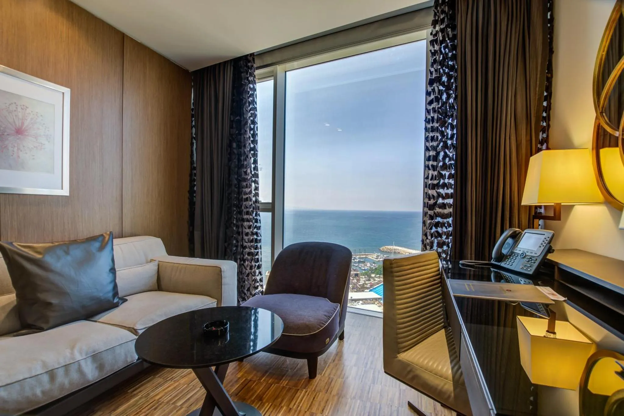 Espace de séjour lumineux avec canapé, fauteuils et vue sur la mer.