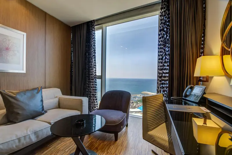 Espace de séjour lumineux avec canapé, fauteuils et vue sur la mer.