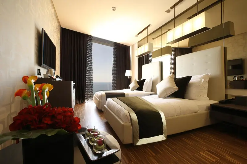 Chambre moderne avec deux lits et vue sur la mer.