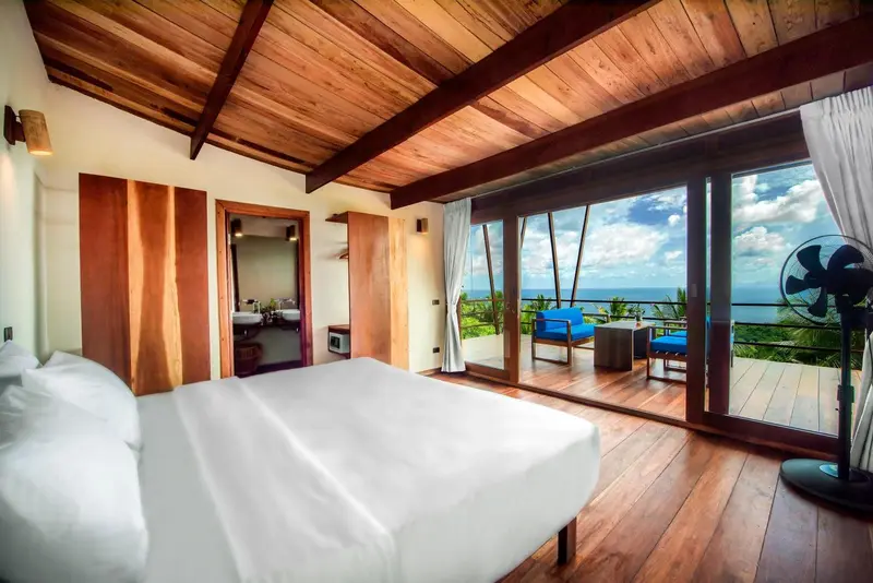 Une chambre lumineuse s'ouvre sur une terrasse avec vue sur la mer.