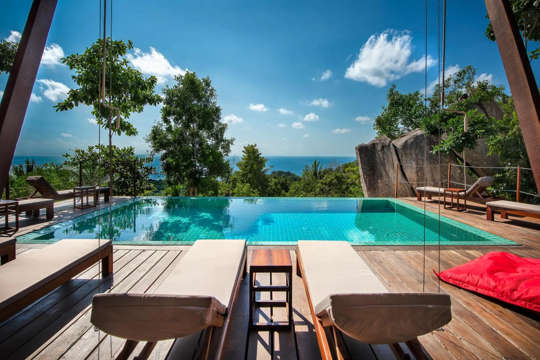 Transats en bois au bord d'une piscine à débordement avec vue sur la mer.