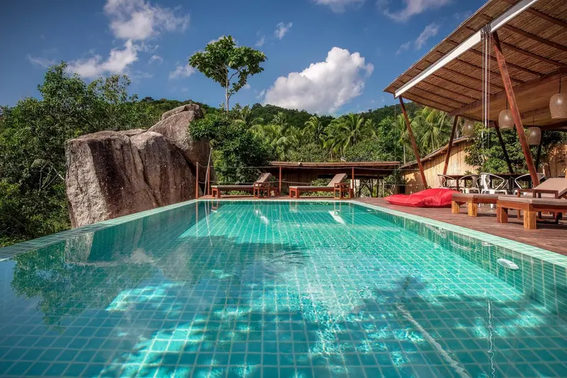 Piscine à débordement avec vue sur la végétation luxuriante et les rochers.
