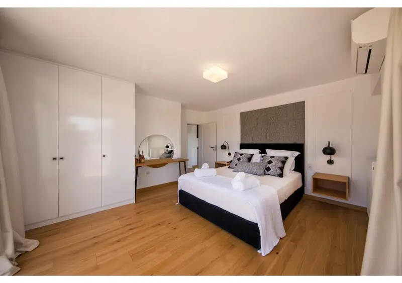Une chambre lumineuse avec un grand lit et un espace bureau.