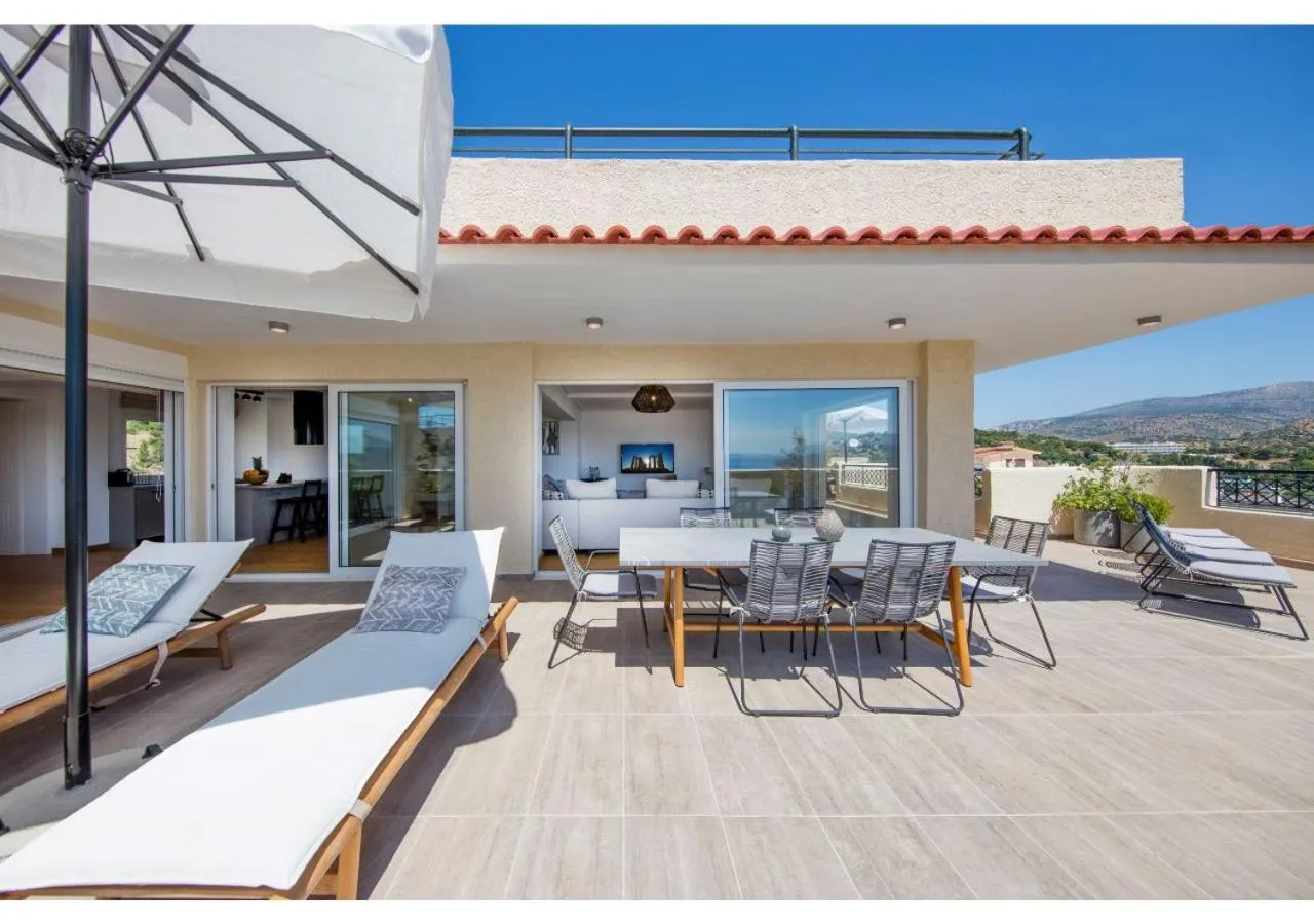 Terrasse aménagée avec transats et table à manger offrant une vue sur la mer.