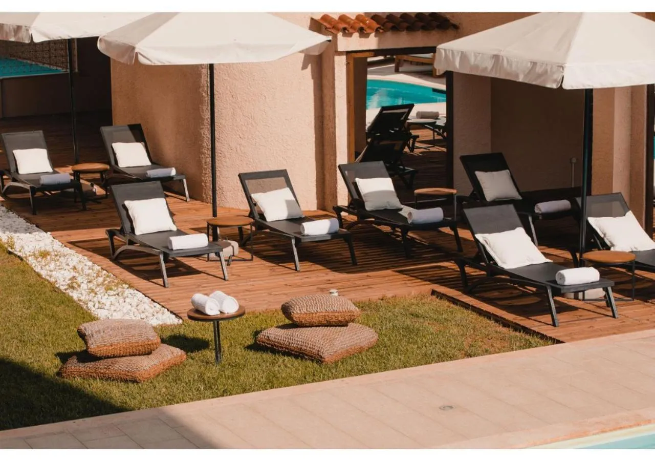 Transats et coussins disposés sur une terrasse en bois près d'une piscine.
