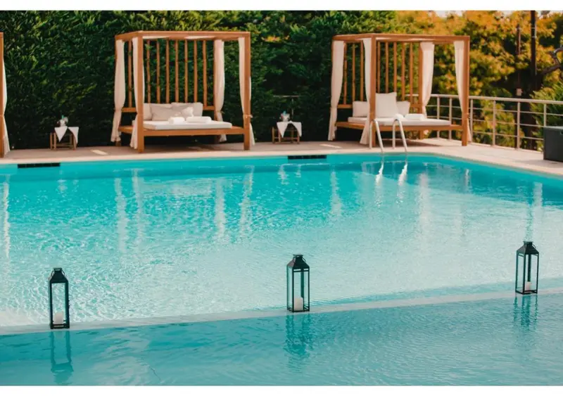 Transats blancs disposés au bord d'une piscine turquoise.