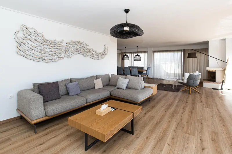 Un grand salon moderne avec un canapé d'angle gris et une table basse en bois.
