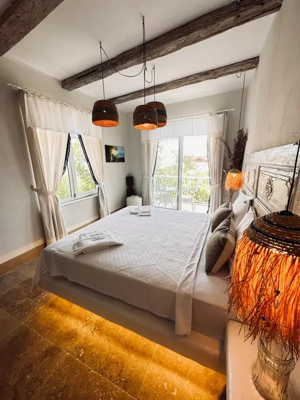 Une chambre lumineuse avec un grand lit et une vue sur la végétation.