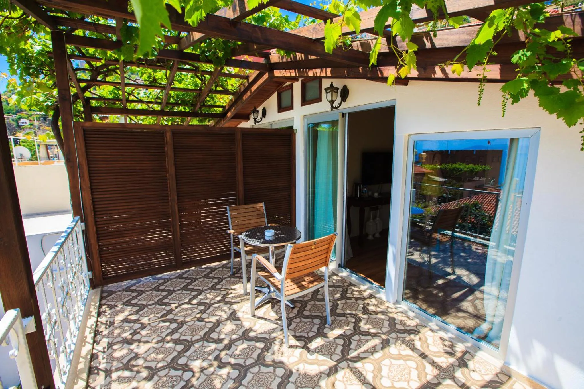 Terrasse carrelée avec table et chaises devant une porte vitrée.