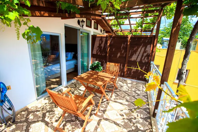 Une terrasse ombragée avec une table et des chaises en bois.