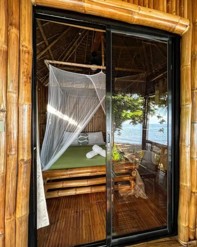 Une chambre avec un lit à baldaquin donnant sur une terrasse et la mer.