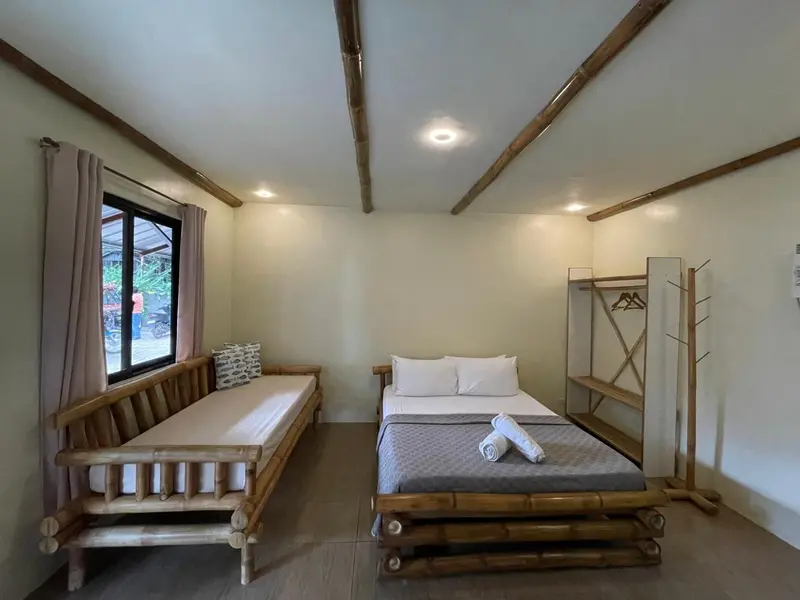 Une chambre lumineuse avec un lit et une banquette en bois.