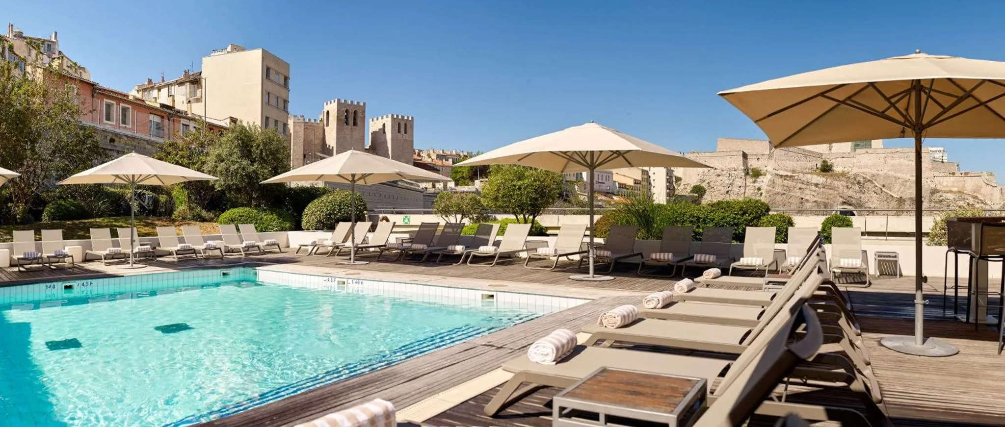 Terrasse avec transats et piscine face à un paysage urbain.