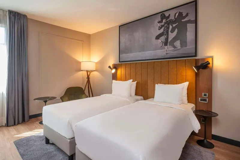 Une chambre lumineuse avec deux lits simples et une décoration murale.