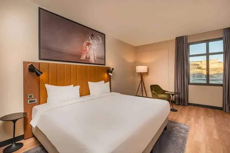 Une chambre lumineuse avec un grand lit et un tableau décoratif.