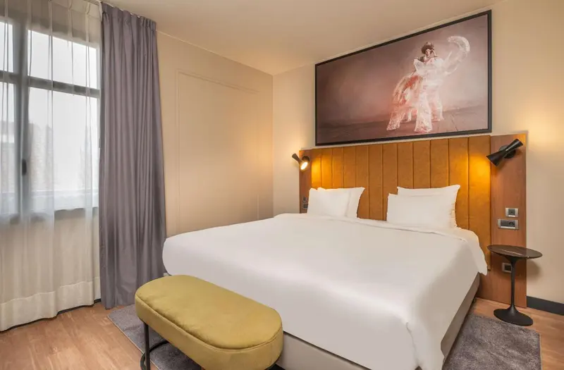 Une chambre d'hôtel lumineuse avec un grand lit et une décoration murale.