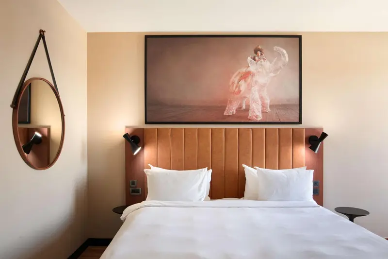 Un lit double avec une tête de lit orange et des oreillers blancs dans une chambre d'hôtel.