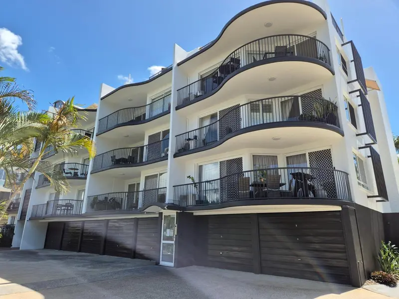 Façade d'un bâtiment blanc à plusieurs étages avec des balcons incurvés.
