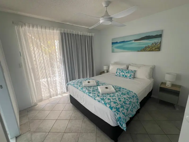 Une chambre lumineuse avec un grand lit recouvert d'une couette à motifs.