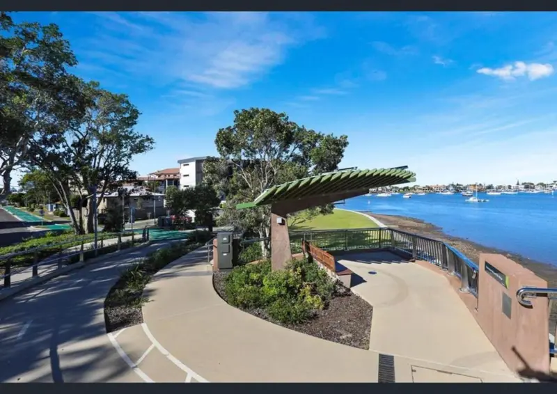 Allée piétonne bordée de verdure et d'une vue sur la mer.