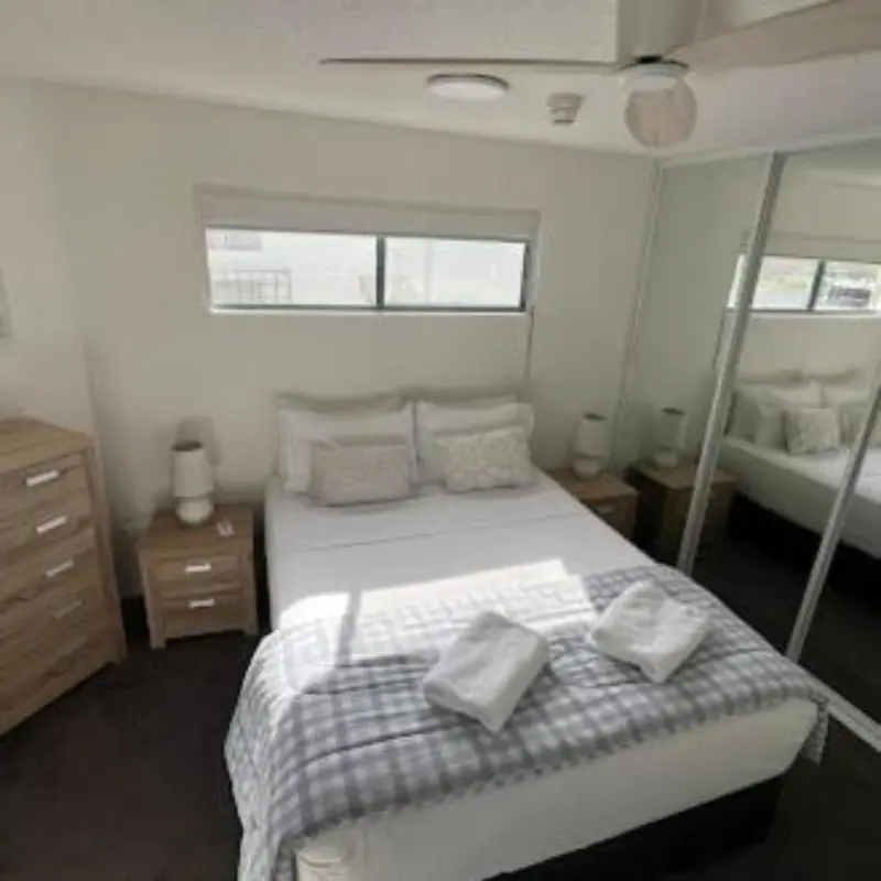 Une chambre lumineuse avec un grand lit et un dressing.