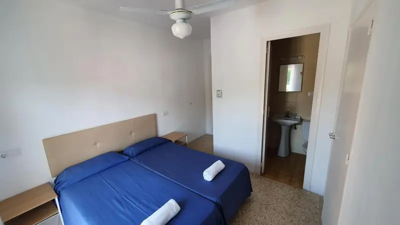 Une chambre lumineuse avec un lit double et un accès à une salle de bain.