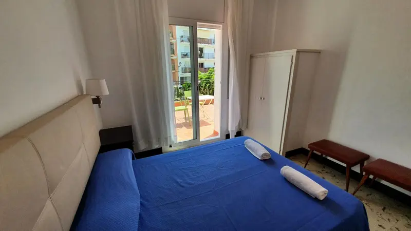 Une chambre lumineuse avec un grand lit et un accès à un balcon.