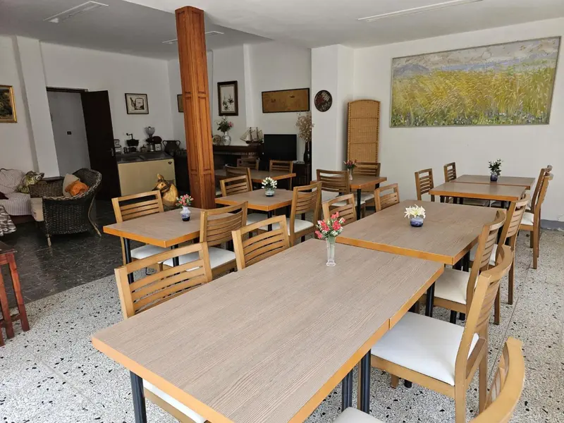 Une salle lumineuse avec des tables et des chaises est décorée de tableaux et de fleurs.