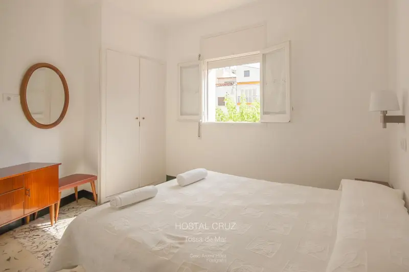 Une chambre lumineuse avec un lit fait et une commode en bois.