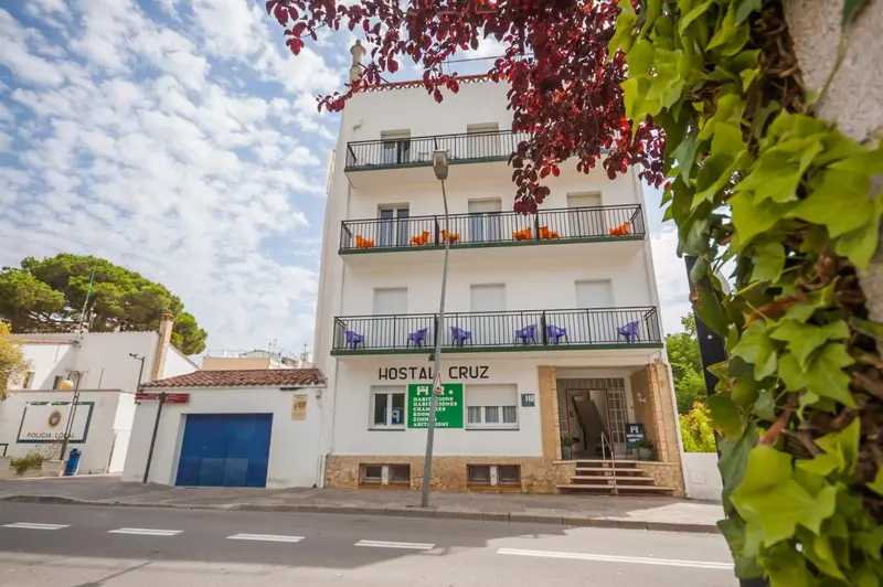 Façade blanche d'un bâtiment à deux étages avec des balcons et de la végétation.