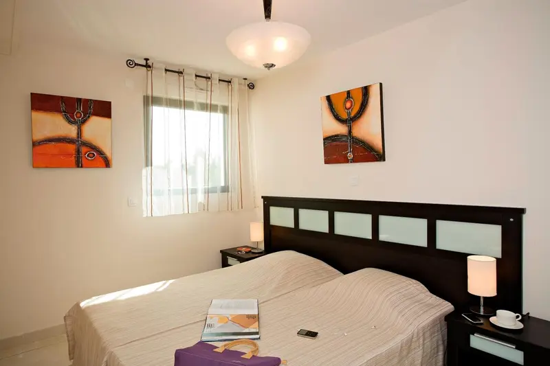 Une chambre lumineuse avec un grand lit et des tableaux décoratifs.