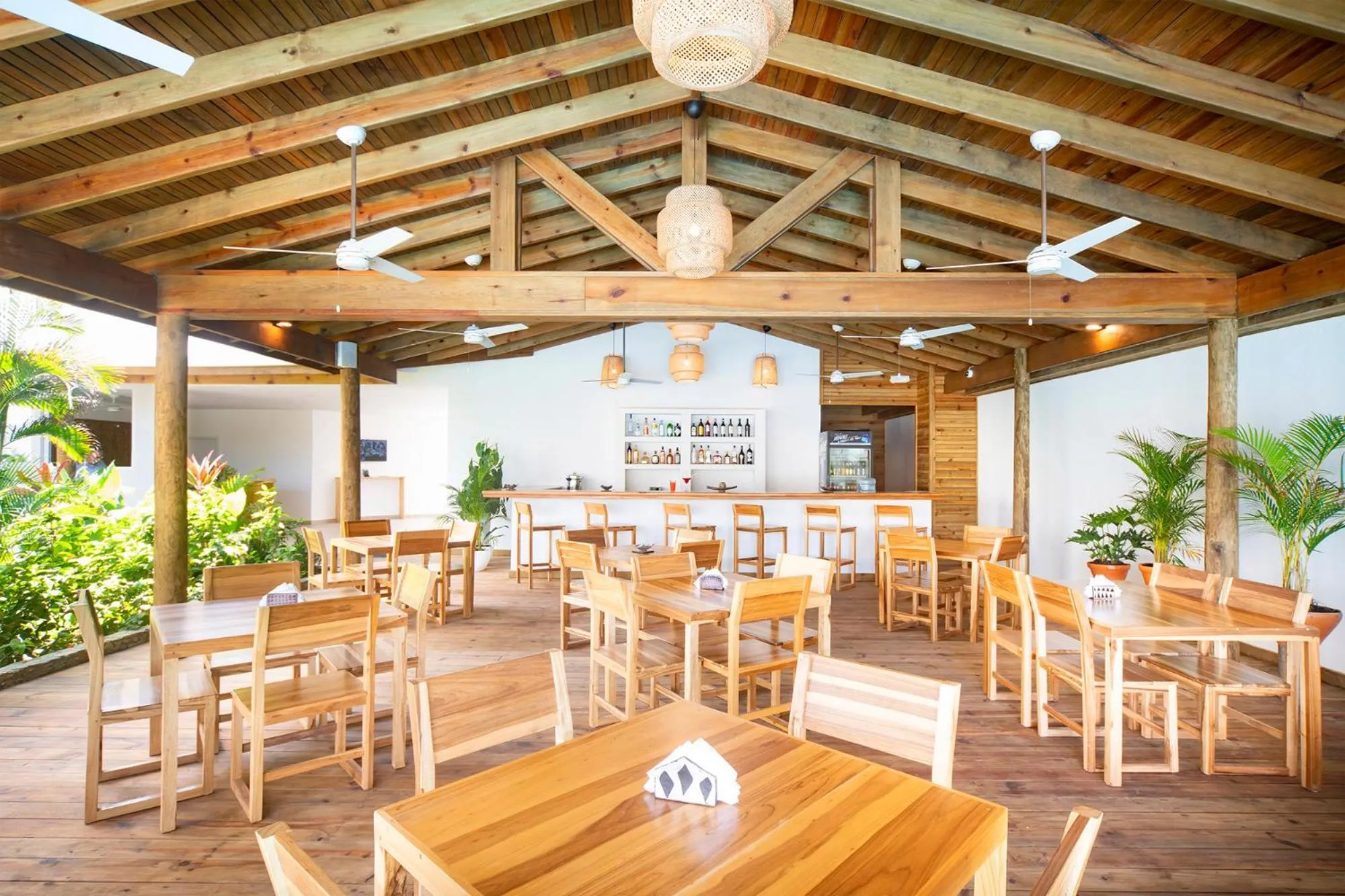Une salle à manger extérieure en bois avec des tables et des chaises.