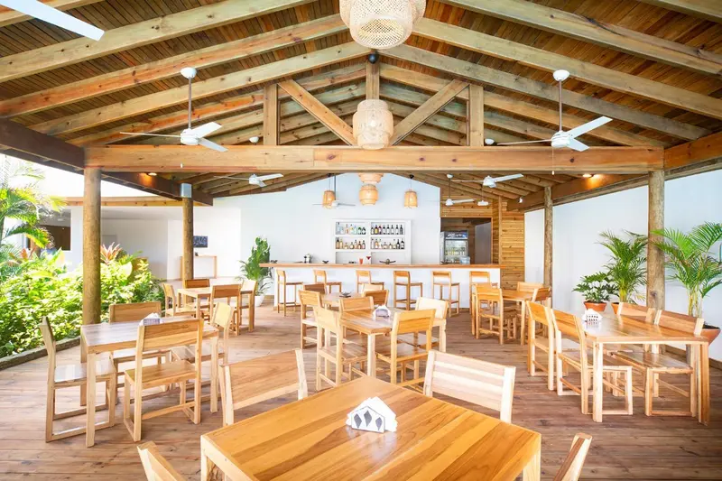 Une salle à manger extérieure en bois avec des tables et des chaises.