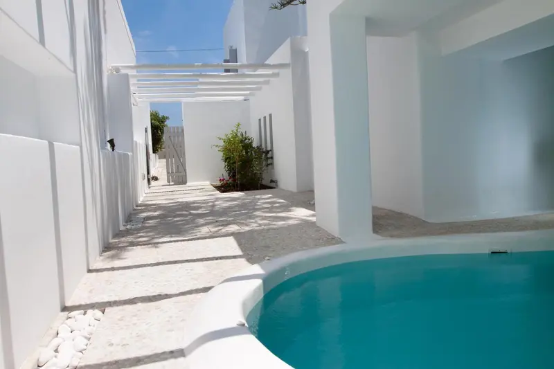 Petite piscine turquoise intégrée à une cour intérieure blanche et lumineuse.