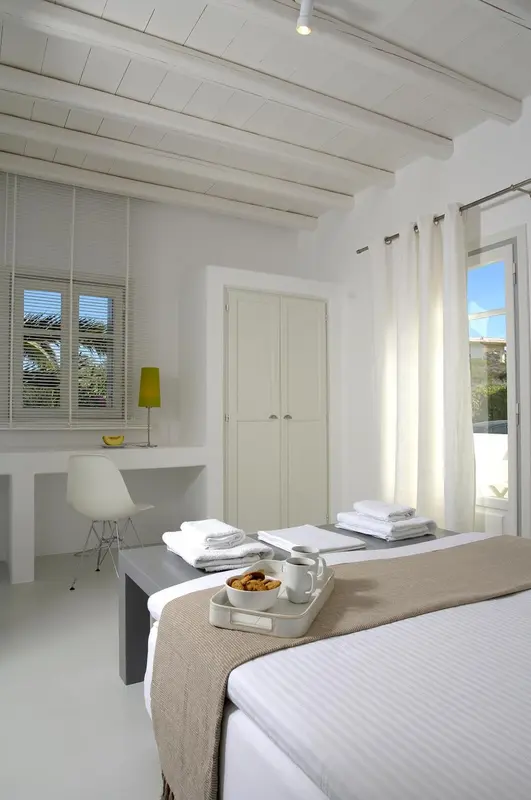 Une chambre lumineuse avec un lit fait et un plateau de petit-déjeuner.