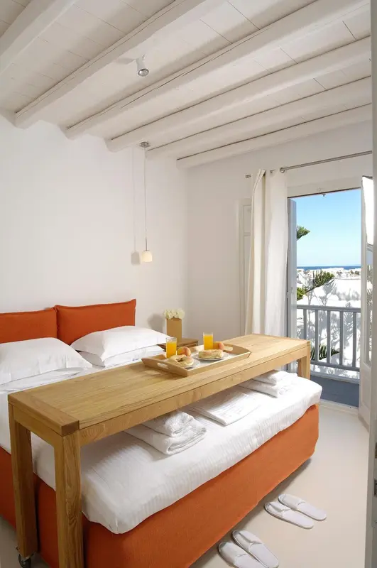 Une chambre lumineuse avec un lit orange et une table basse servant de plateau petit-déjeuner.