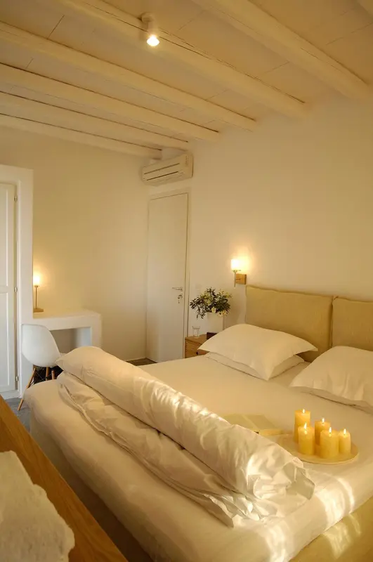 Une chambre lumineuse avec un lit fait et des bougies.