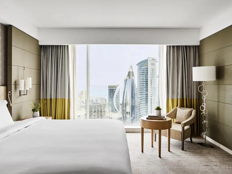 Une chambre lumineuse avec un grand lit et une vue sur la ville.