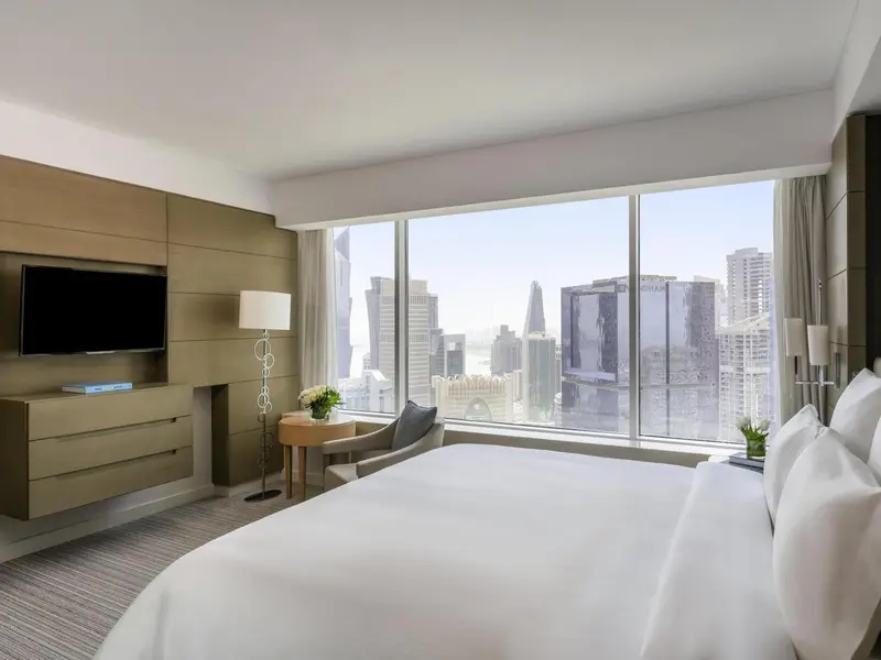 Chambre lumineuse avec un grand lit et une vue sur la ville.