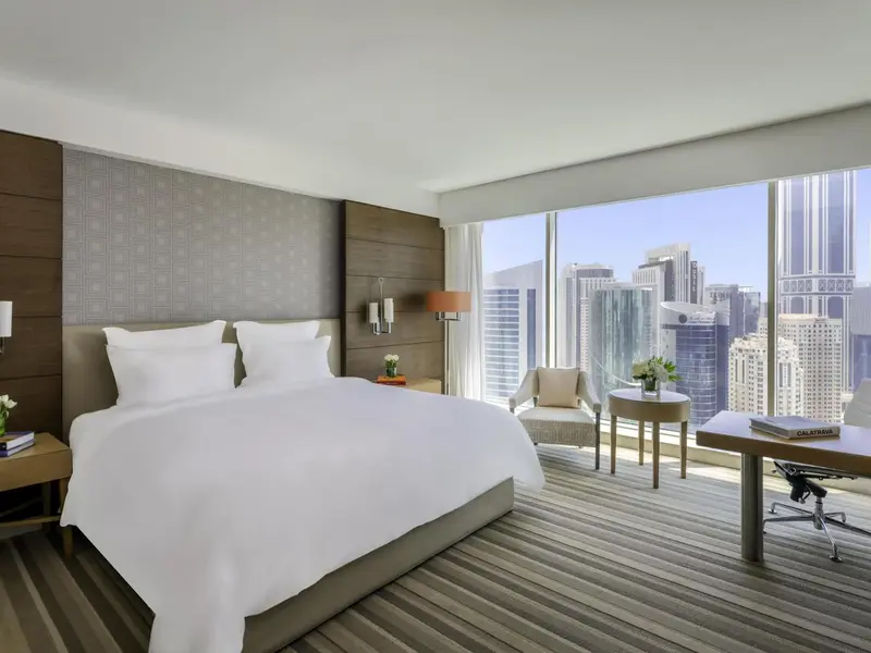 Une chambre lumineuse avec un grand lit et une vue sur la ville.