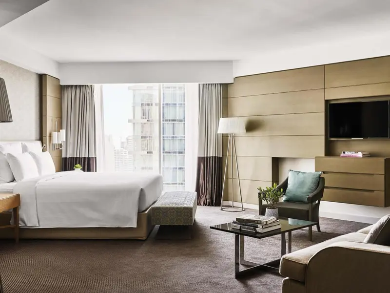 Chambre lumineuse avec un grand lit et un coin salon.