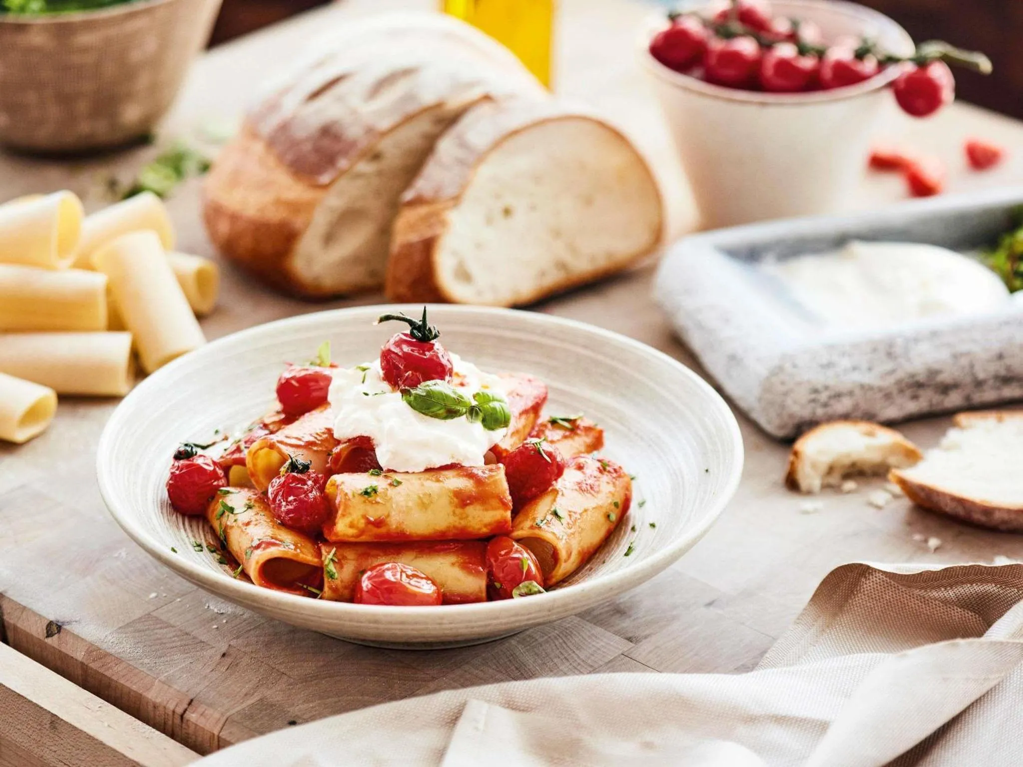 Assiette de pâtes fraîches à la sauce tomate et au fromage, accompagnée de pain et de cerises.