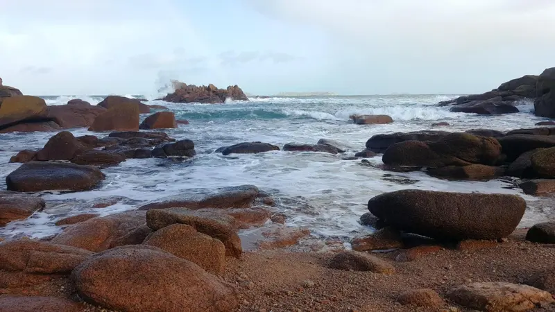 Rochers et vagues sur une plage rocheuse.