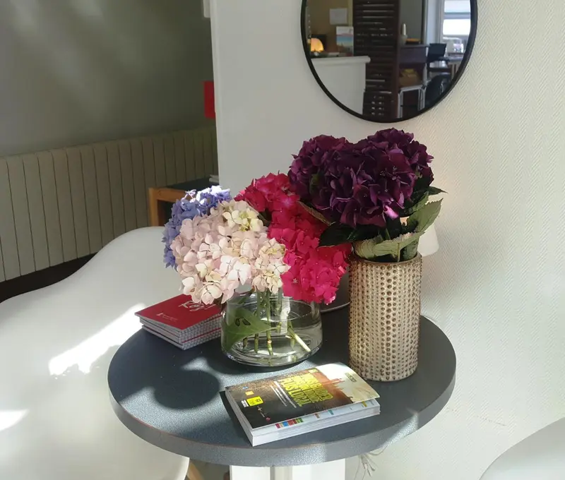 Une table ronde avec un arrangement floral et des brochures.