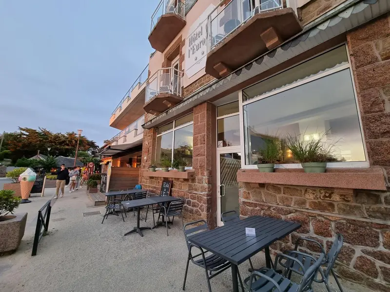 Façade d'un bâtiment avec une terrasse et des tables de restaurant.
